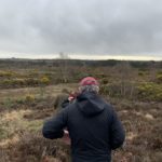 Photo of wardens walking down a heath-clad slope, with heath stretching off into the distance.