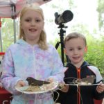 Photo of a little girl and a little boy proudly holding the Nightjar nests they've made