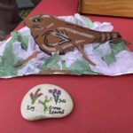 Photo of a paper Nightjar and a pebble decorated with heather.