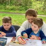 Photo of a mum and two boys colouring in paper snakes.