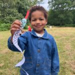 Nice photo of a small biy holding up the paper snake he's created.