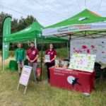 Photo of two bright gazebos and three staff members, one from Forestry England in green uniform, two from Thames Basin Heaths Partnership in burgundy.