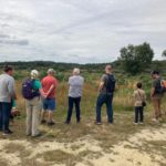 Photo of some people standing on a heathland, looking out over the view.