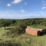 Photo of the view from the top of the hill. A pillbox in the foreground. View out over attractive countryside beyond.